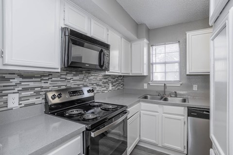 A modern kitchen with white cabinets and stainless steel appliances.